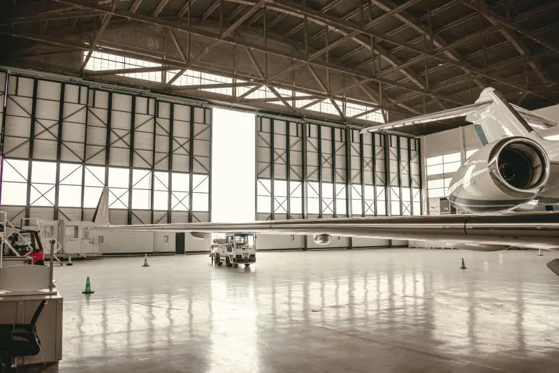 Business jet parked inside a clean, bright maintenance hangar