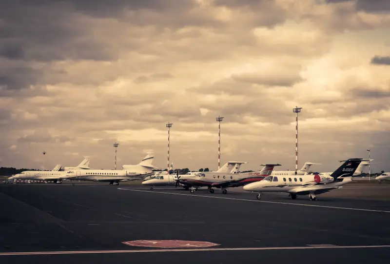 Row of business jets parked on a ramp under a dramatic dusk sky